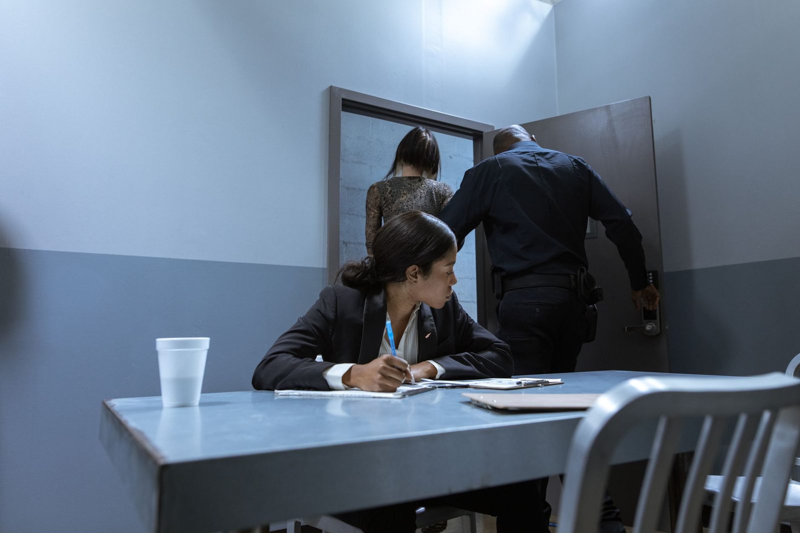 Lawyer observing police interrogation with suspect and officer present.