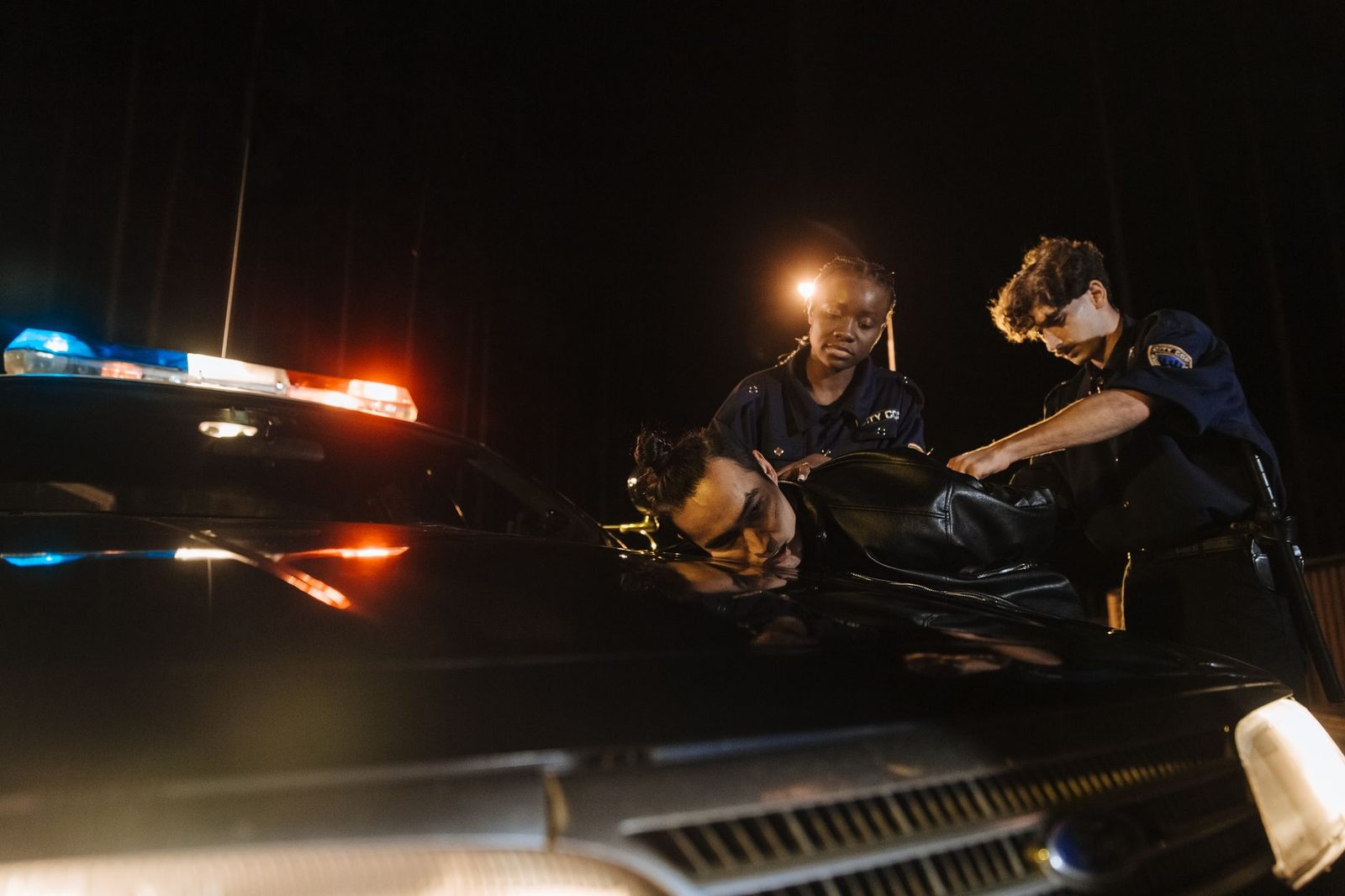 Policías deteniendo a sospechoso junto a patrulla nocturna.