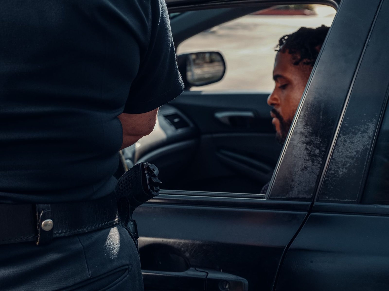 Police officer issuing a traffic ticket to a driver during a daytime traffic stop.