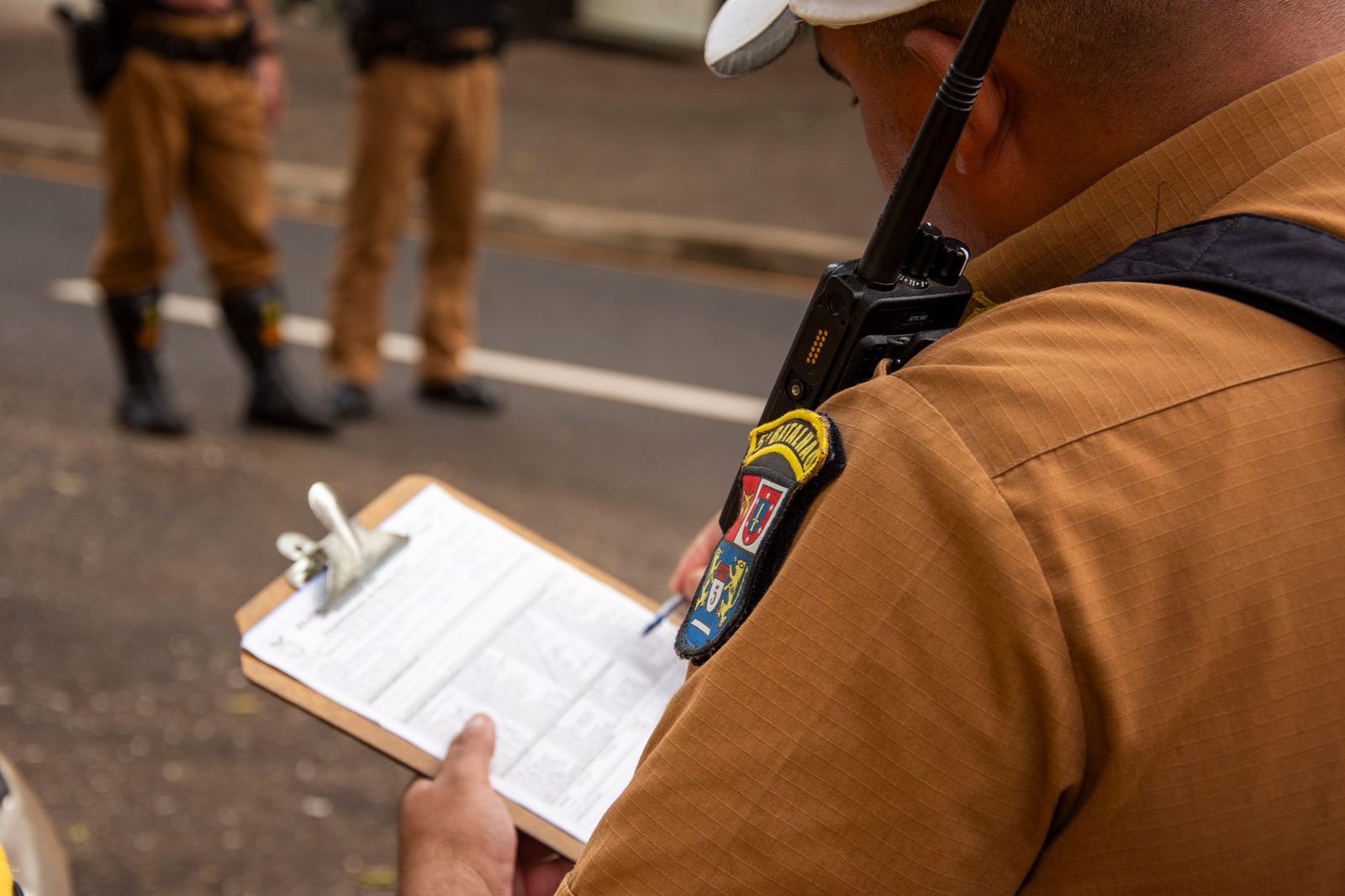 Police officer writing on clipboard outdoors.