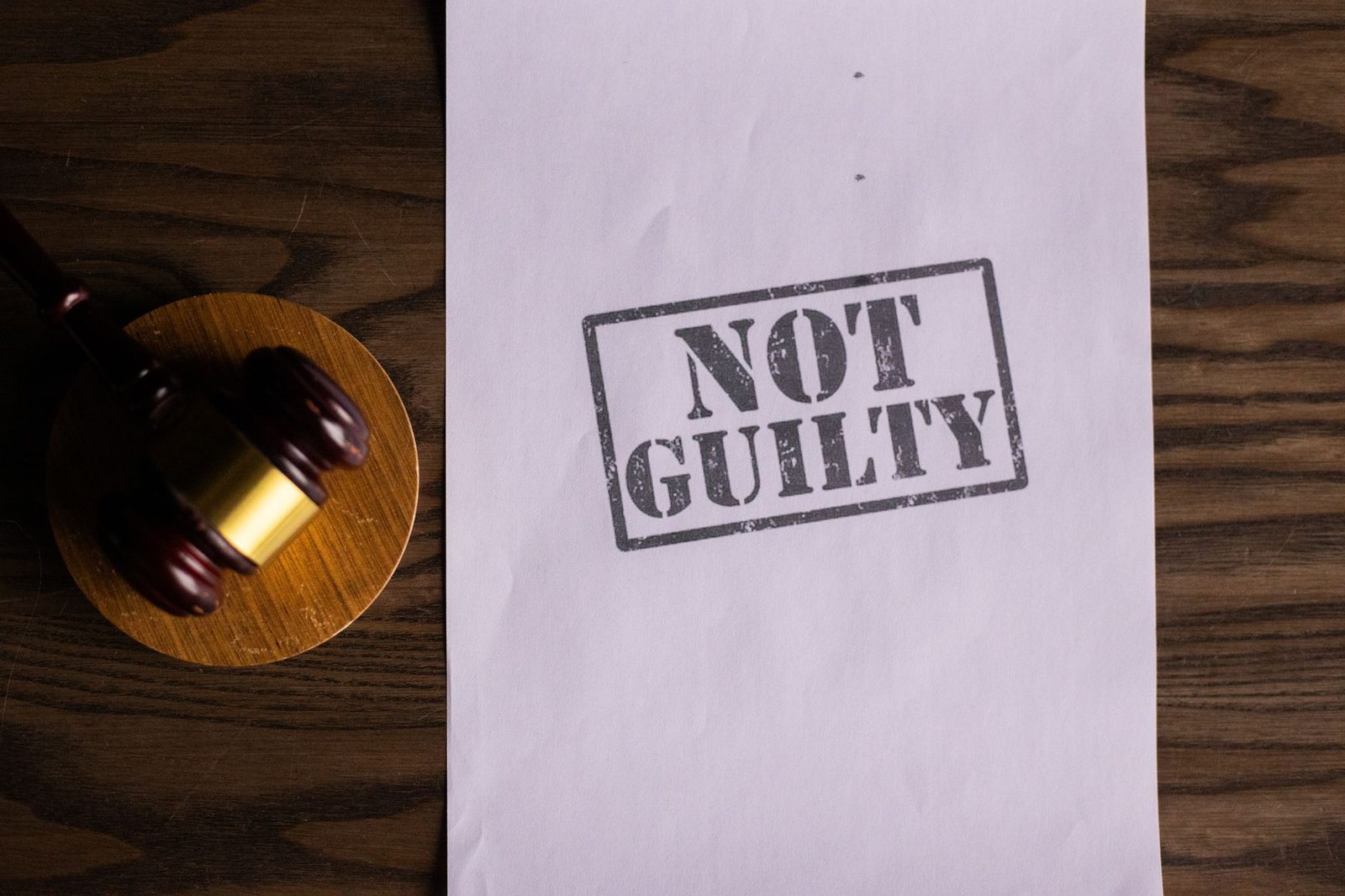 A gavel resting beside a court document stamped "Not Guilty" on a wooden surface.