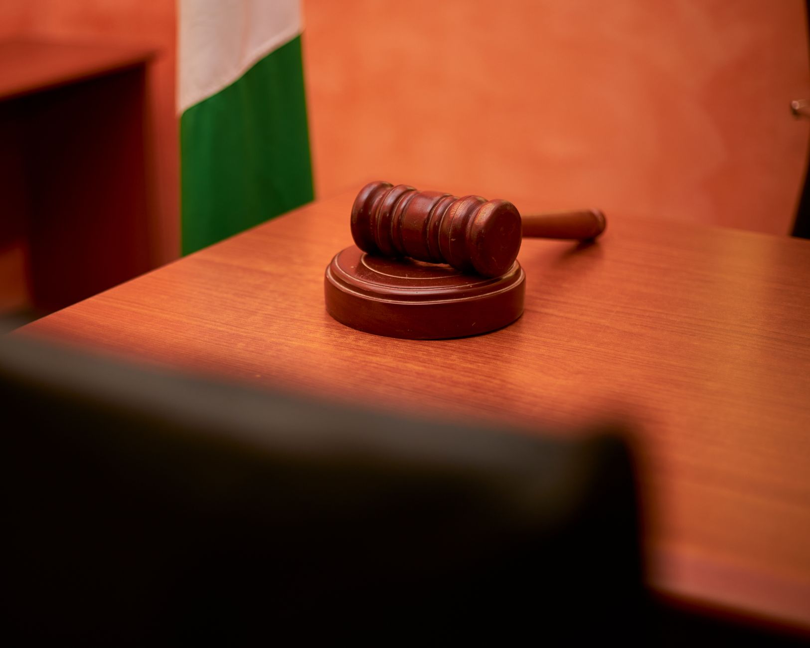 A gavel resting on a wooden courtroom desk, symbolizing law and justice.
