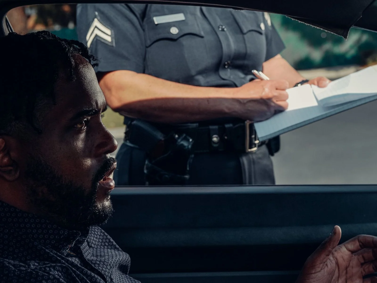 A police officer hands a ticket to a driver during a roadside traffic stop.