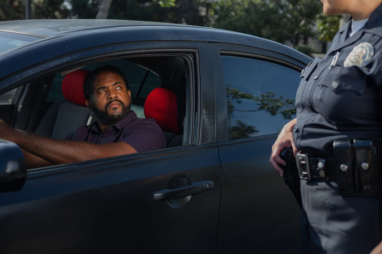A police officer hands a traffic ticket to a driver through a car window.