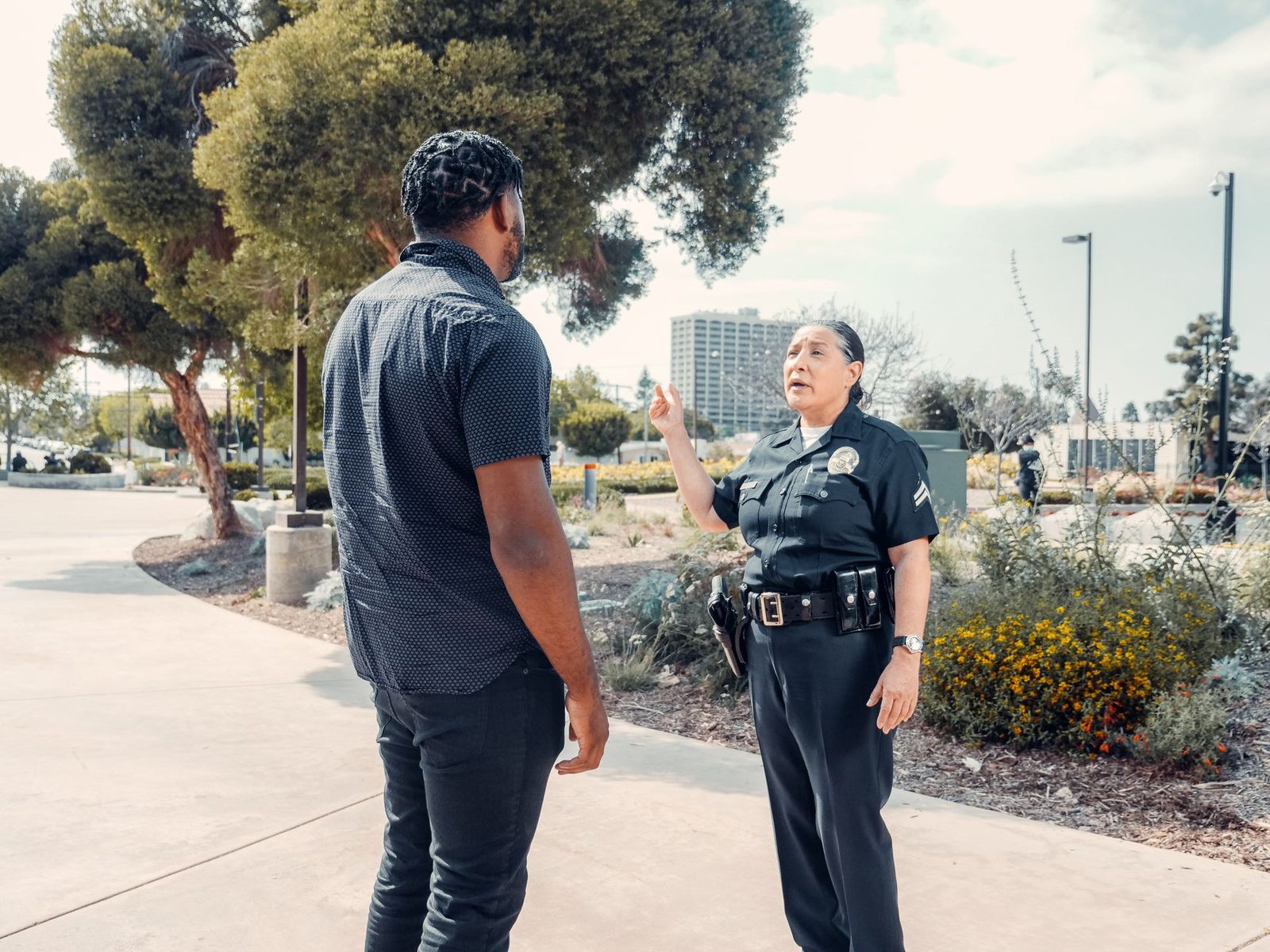 A police officer talks with a civilian in a sunny park.