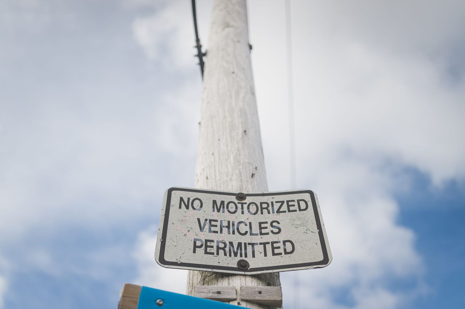 Señal de tráfico que prohíbe vehículos motorizados sobre un poste, con cielo azul de fondo.
