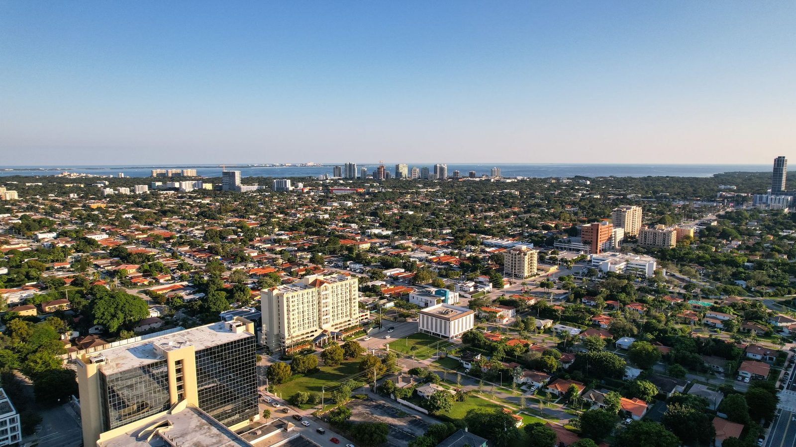 Vista aérea diurna del skyline de Miami con el océano extendiéndose hacia el horizonte.