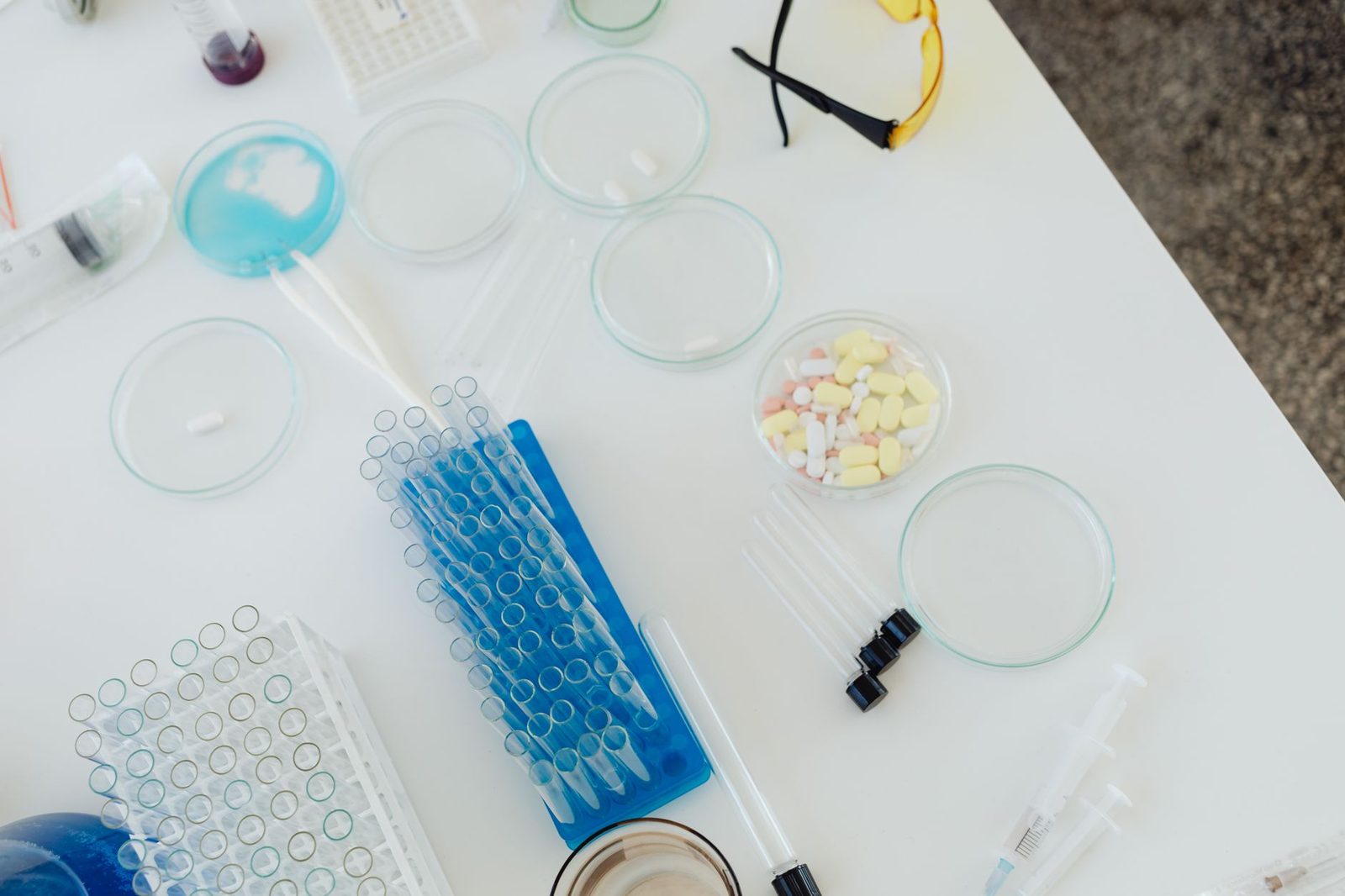 Aerial view of a lab bench with petri dishes, pills, test tubes, and syringes.