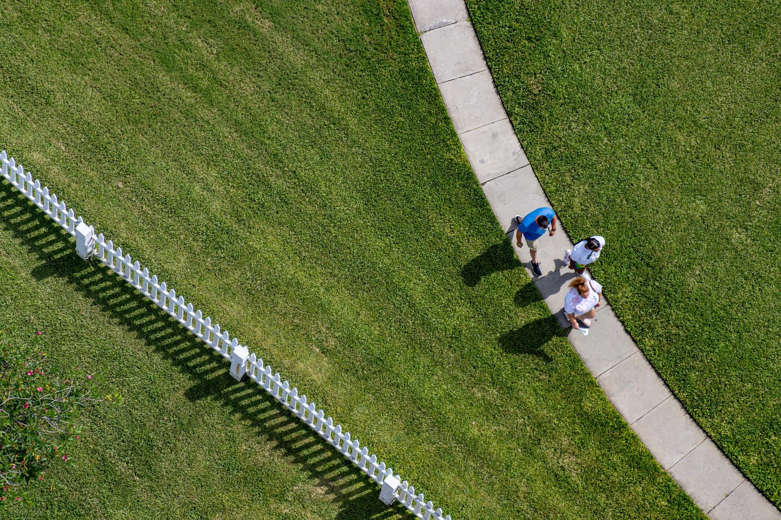 Vista aérea de personas caminando por una acera curva junto a una cerca blanca en Ponce Inlet, Florida.