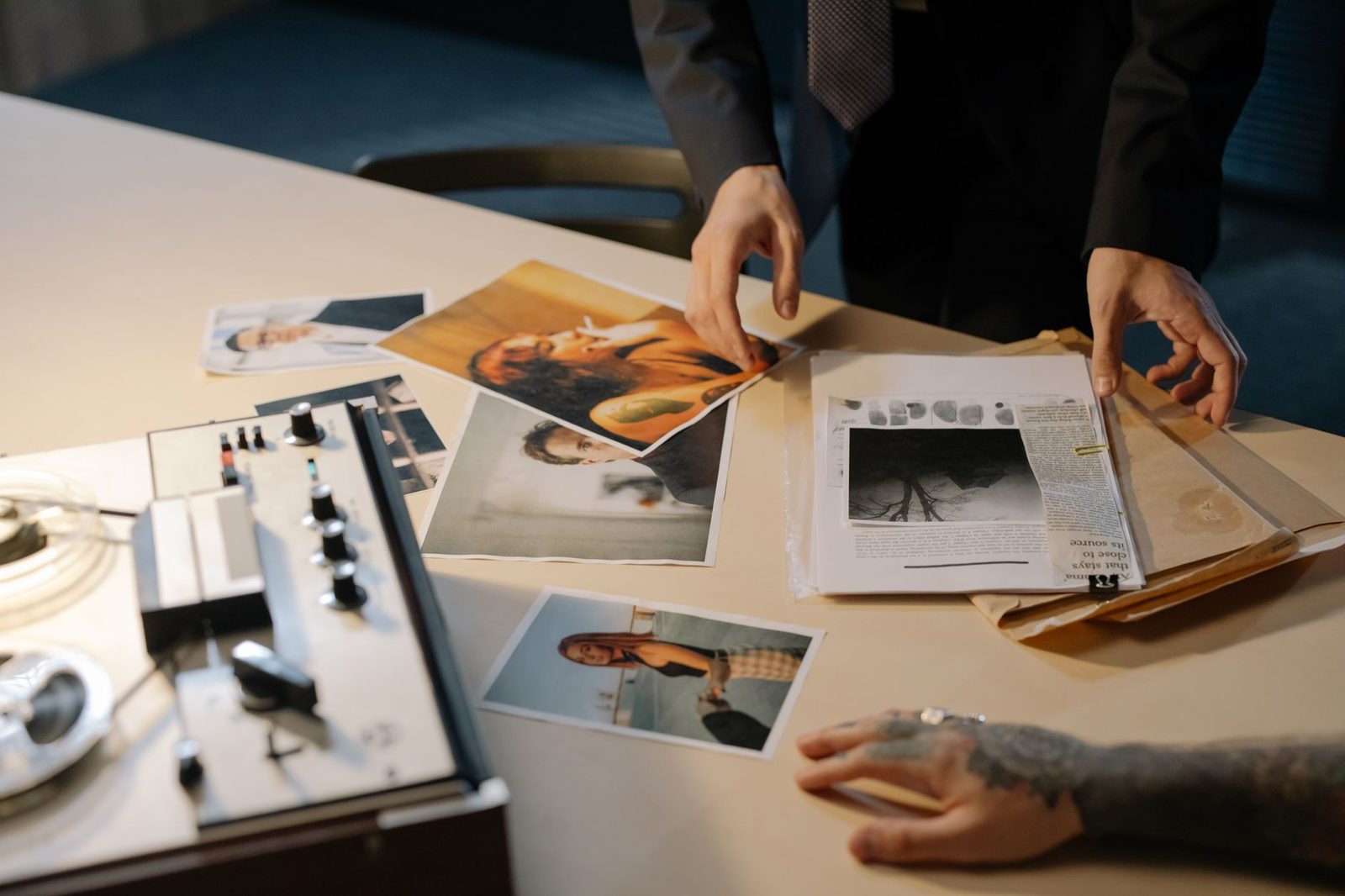 Detective reviewing case evidence and photographs on desk.