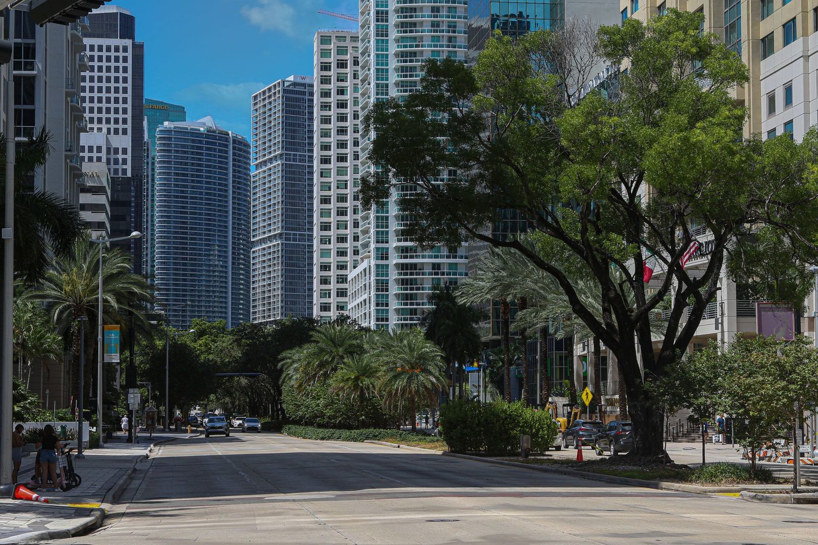 Calle del centro de Miami flanqueada por rascacielos altos y palmeras bajo un cielo azul brillante.