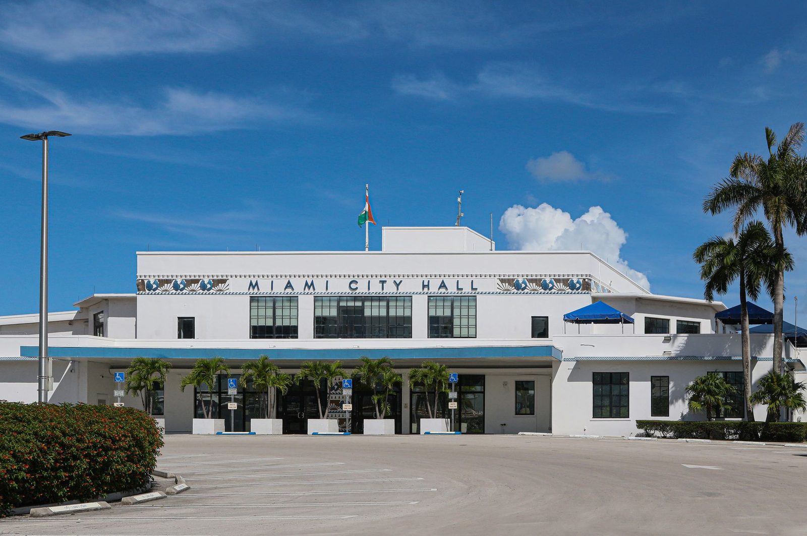 Fachada del Ayuntamiento de Miami con palmeras bajo un cielo azul despejado.
