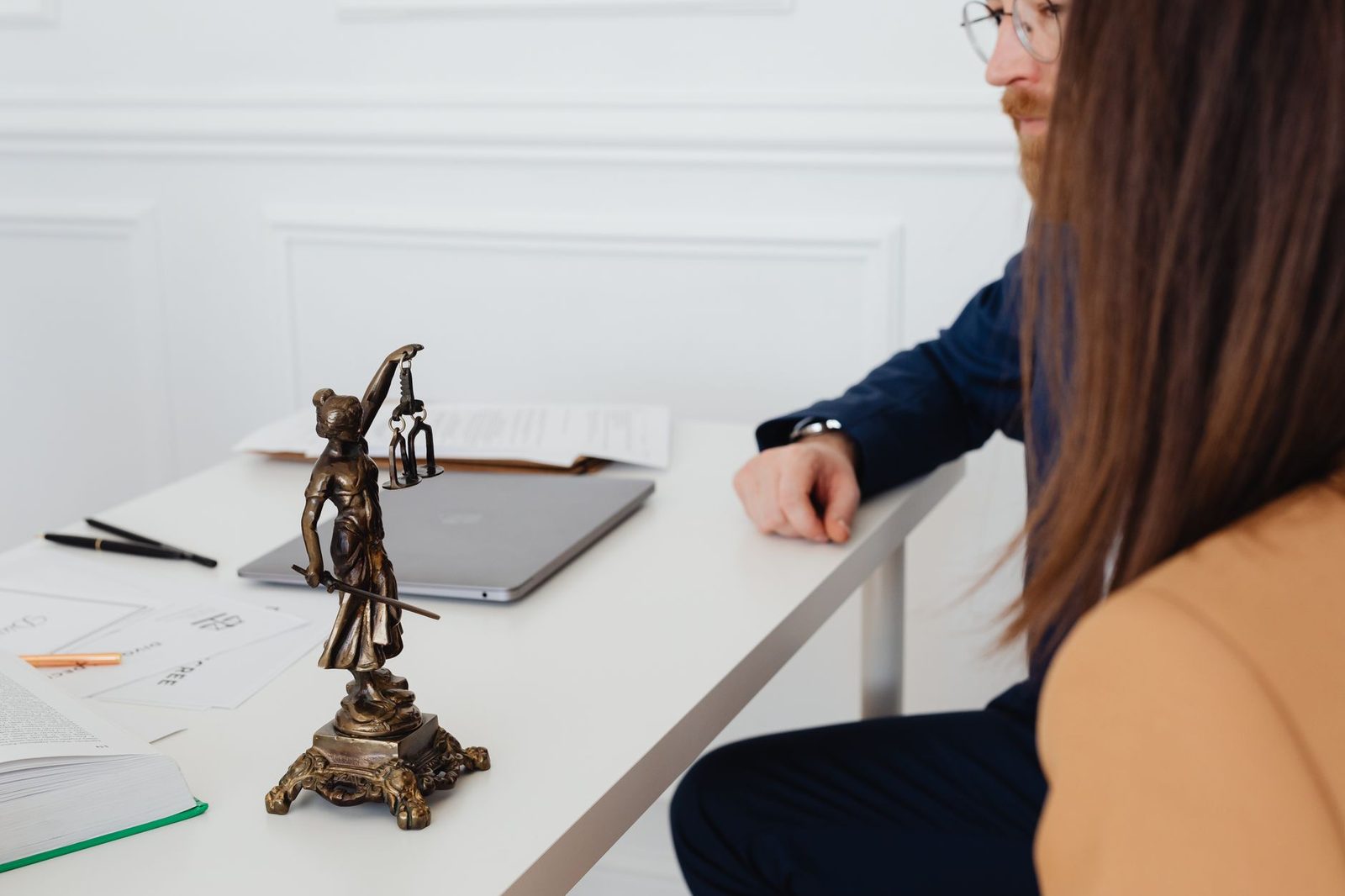Lawyers reviewing legal documents with Lady Justice statue in professional office.