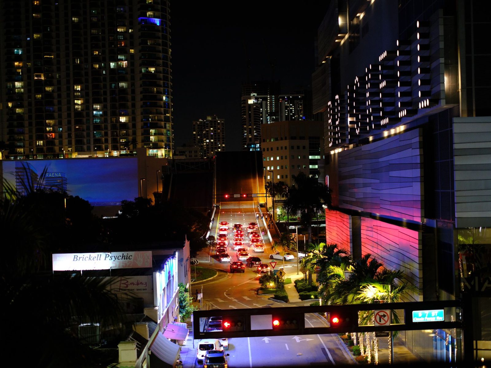 Night view of Miami's Brickell skyline, with glowing skyscrapers and busy traffic below.