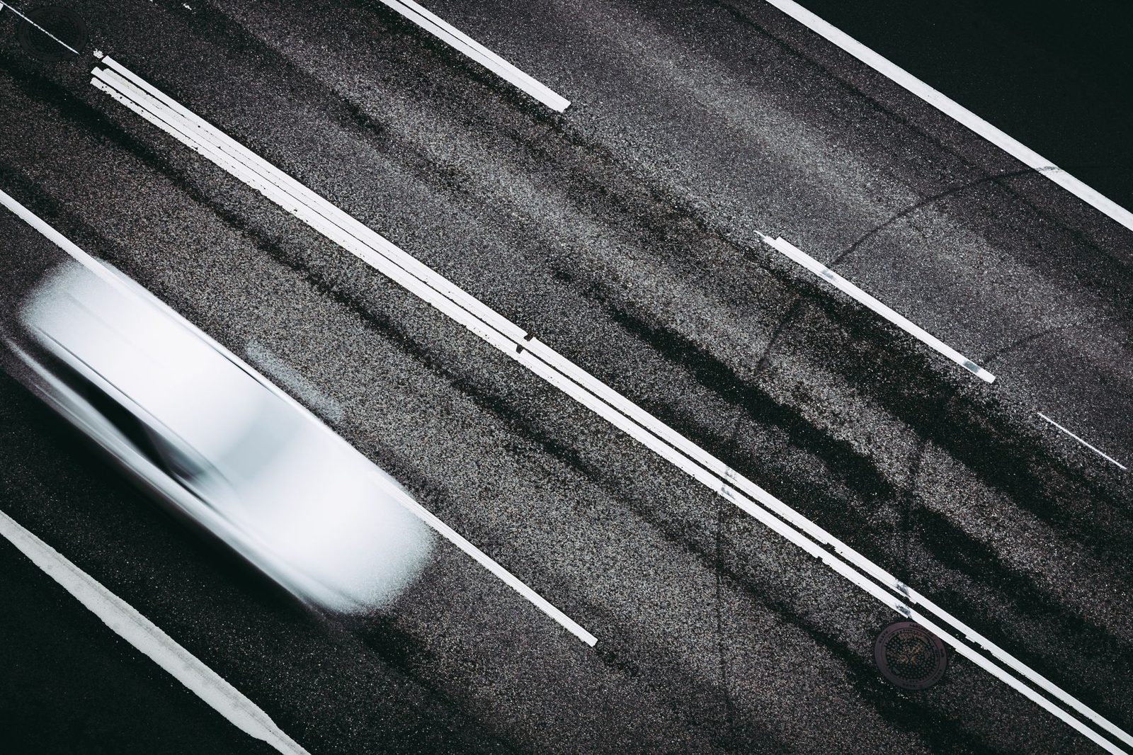 Overhead view of a highway with a car blurred by motion as it passes.