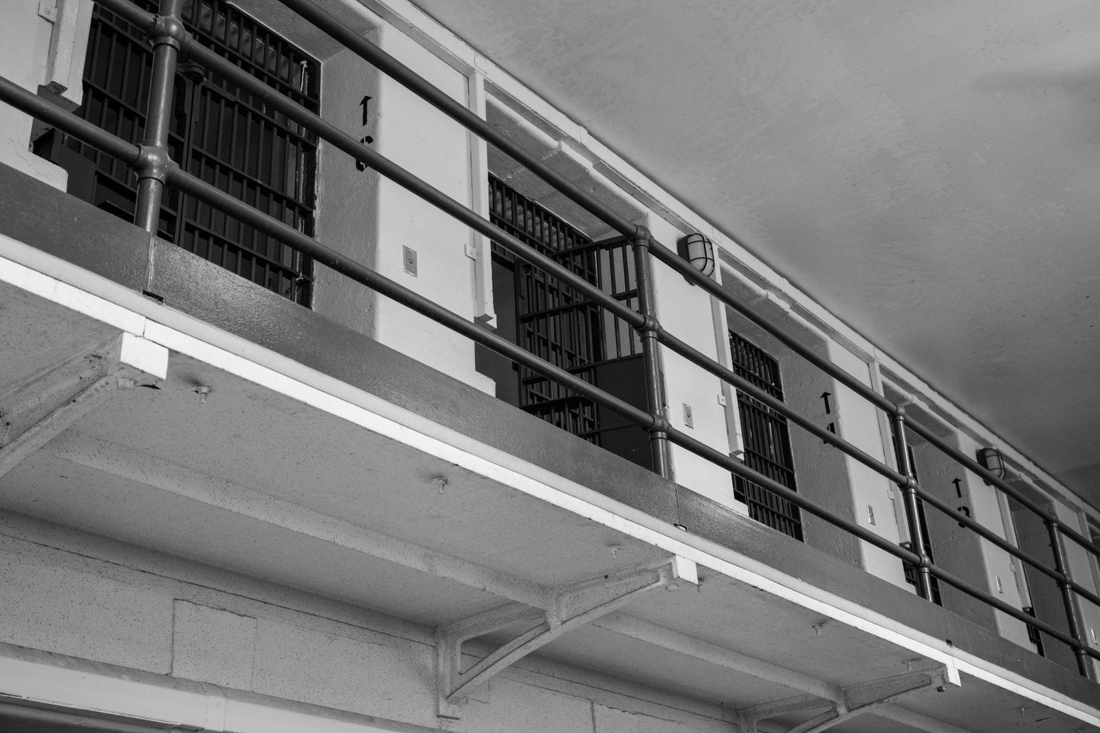Pasillo de celdas de prisión con puertas enrejadas en blanco y negro.