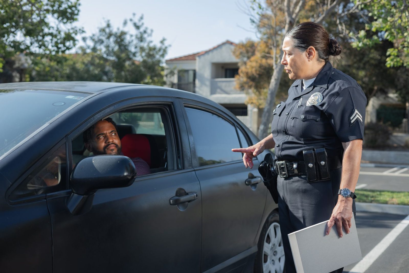 Police officer conducting a traffic stop with a driver on a residential street.