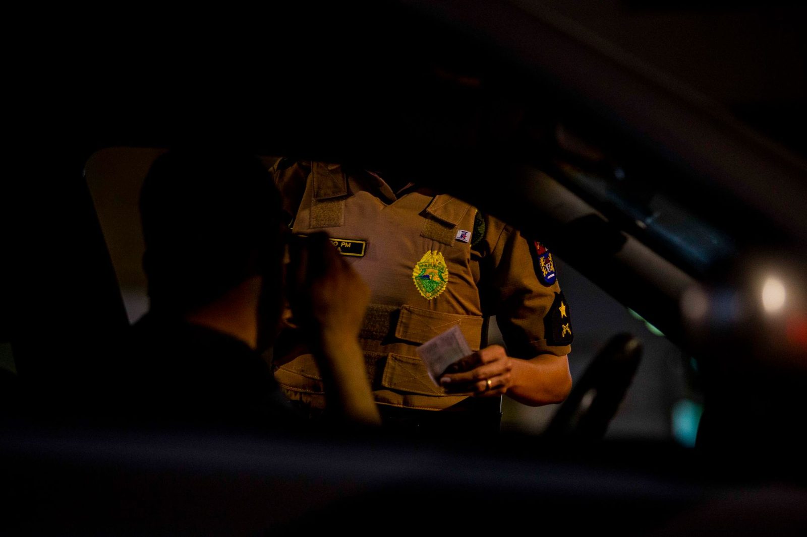 Police officer inspecting a vehicle during a nighttime traffic stop.