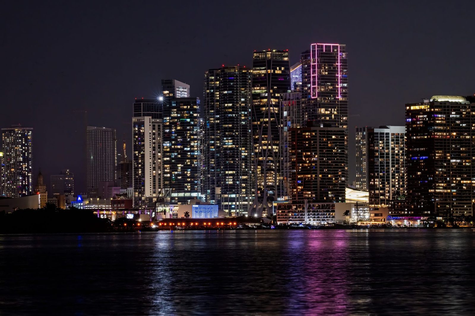 Skyline iluminado de Miami reflejado en el agua durante la noche.