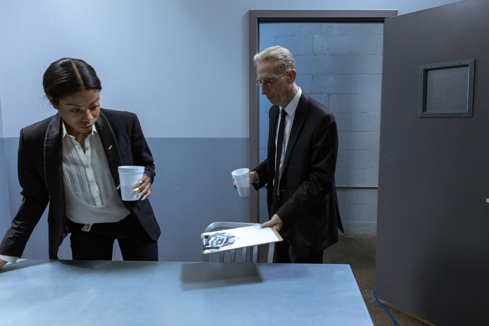 Dos profesionales conversan y revisan documentos confidenciales juntos en una oficina con tomas de café.