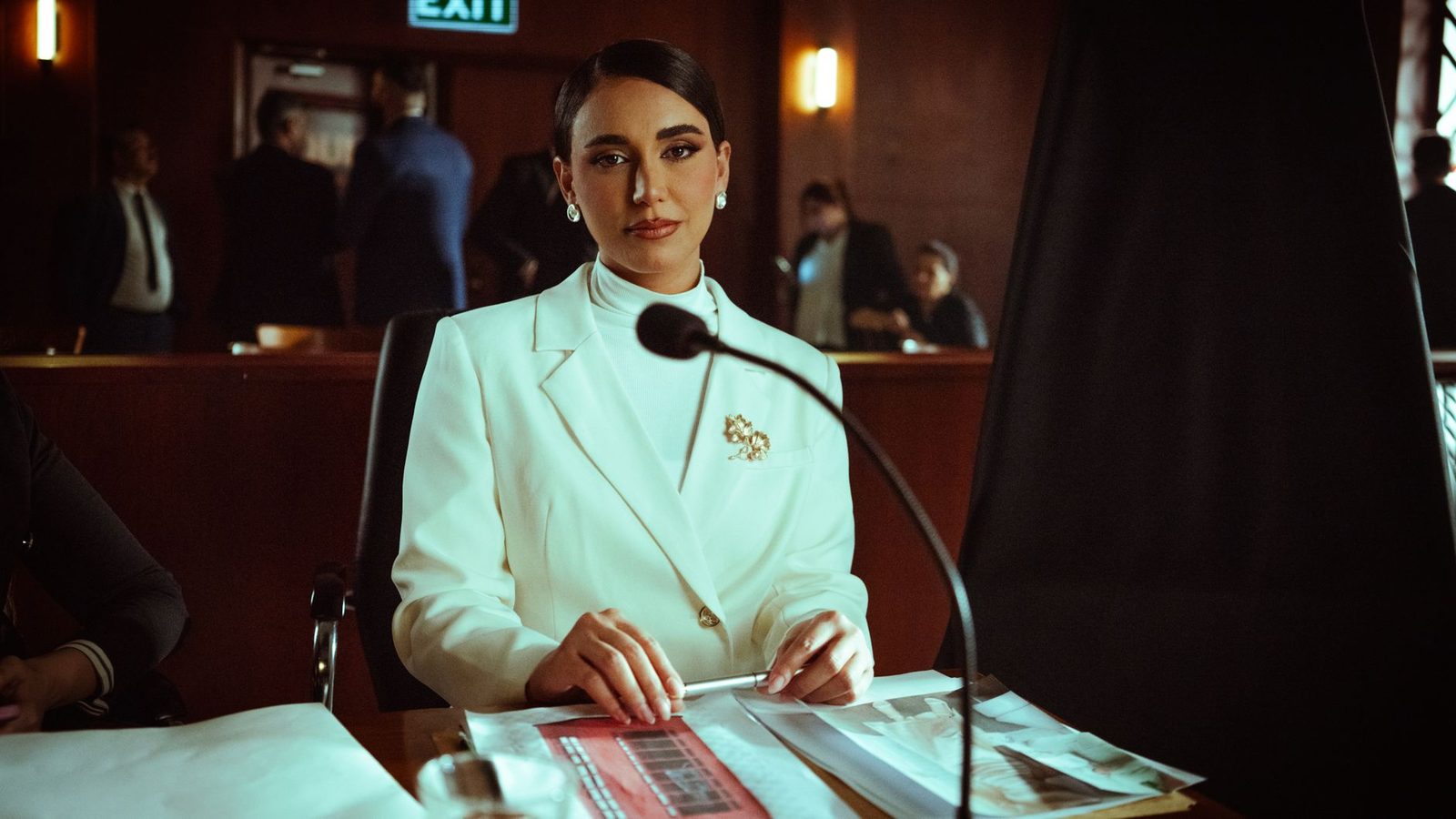 Woman in white suit sitting confidently in a courtroom.